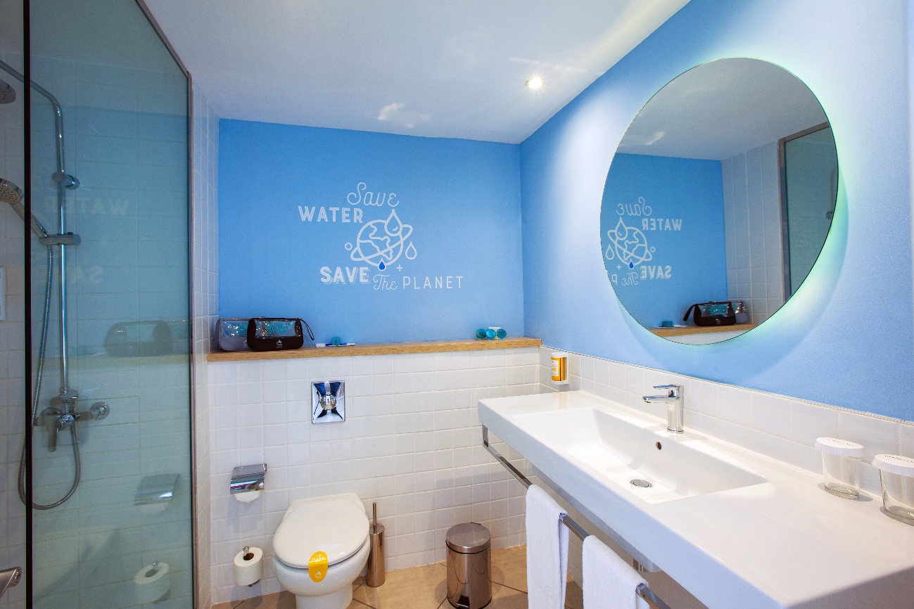 Baño con lavabo, espejo redondo iluminado y ducha