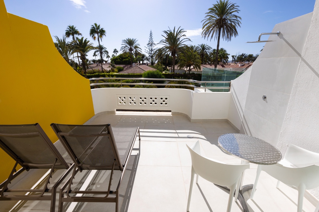 Terraza privada con dos tumbonas, mesa y ducha exterior