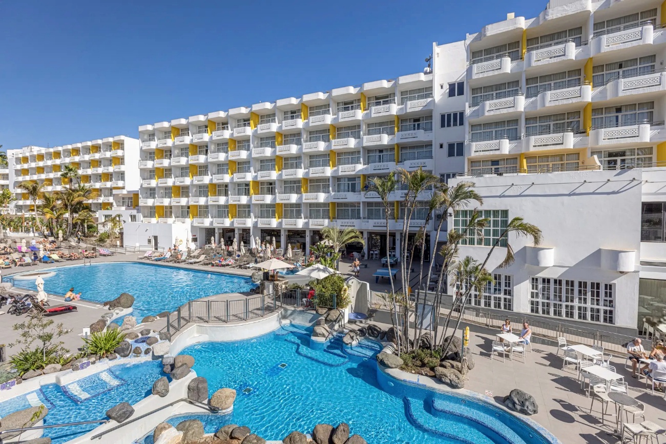 Piscinas del Abora Catarina junto a la fachada blanca y amarilla del hotel